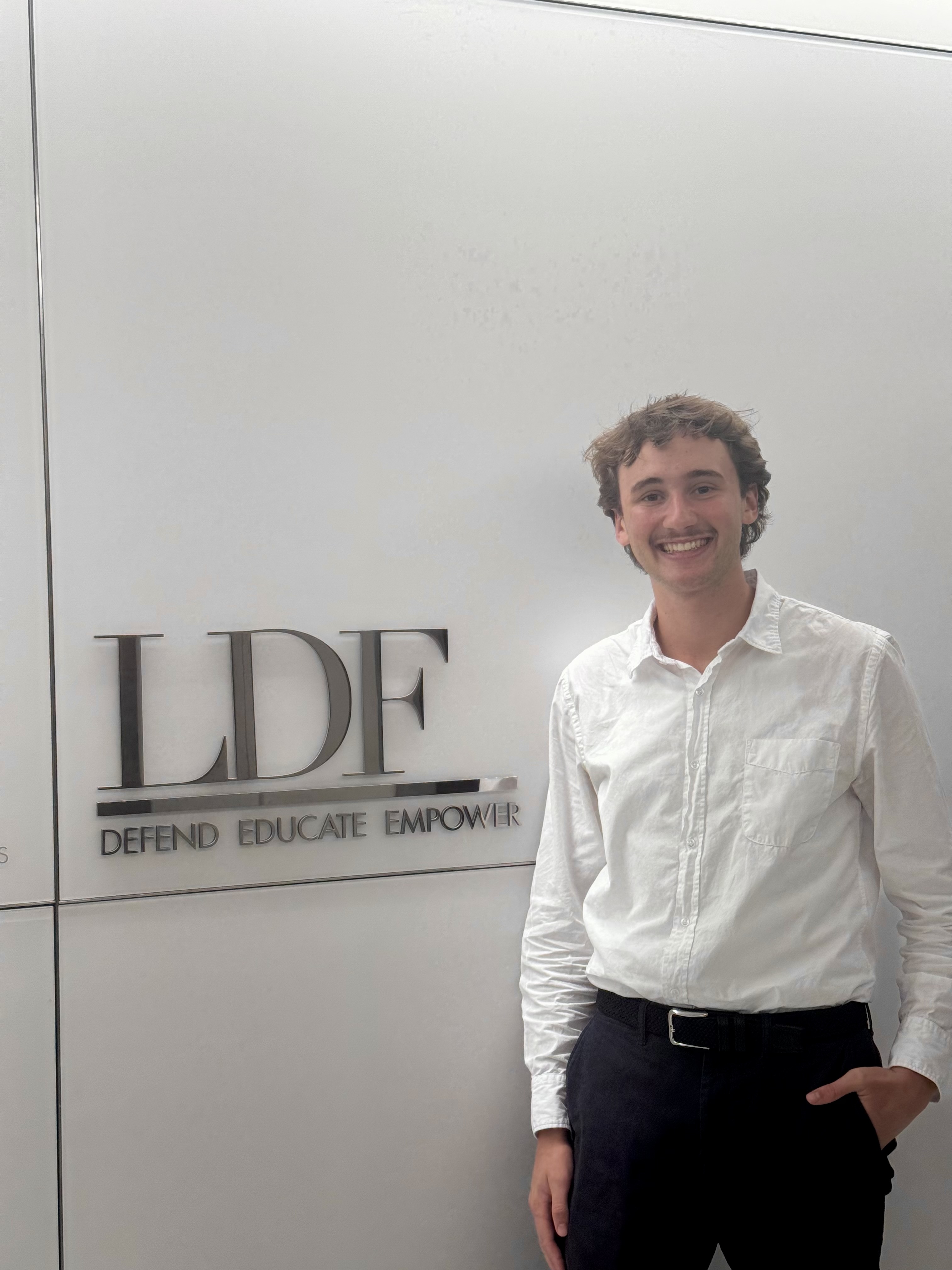 Mack Levy ’27 worked as an Undergraduate Research Fellow at the Thurgood Marshall Institute (TMI) this past summer, where he conducted social science research, wrote briefs, and developed an interactive workshop on gentrification and Black political power. Photo taken in Summer 2025 in front of an LDF sign at the NAACP Legal Defense Fund's New York headquarters and provided by Levy.