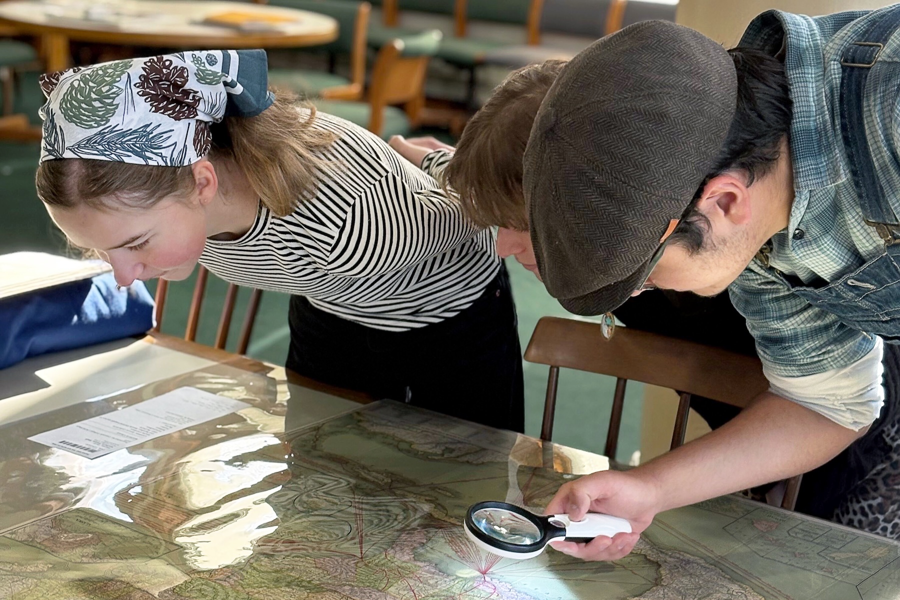 (From left) Emma Snow '26, Jeremy Jarecki '26, and Felipe Singer '26 study a map in the Newberry Library in Chicago.