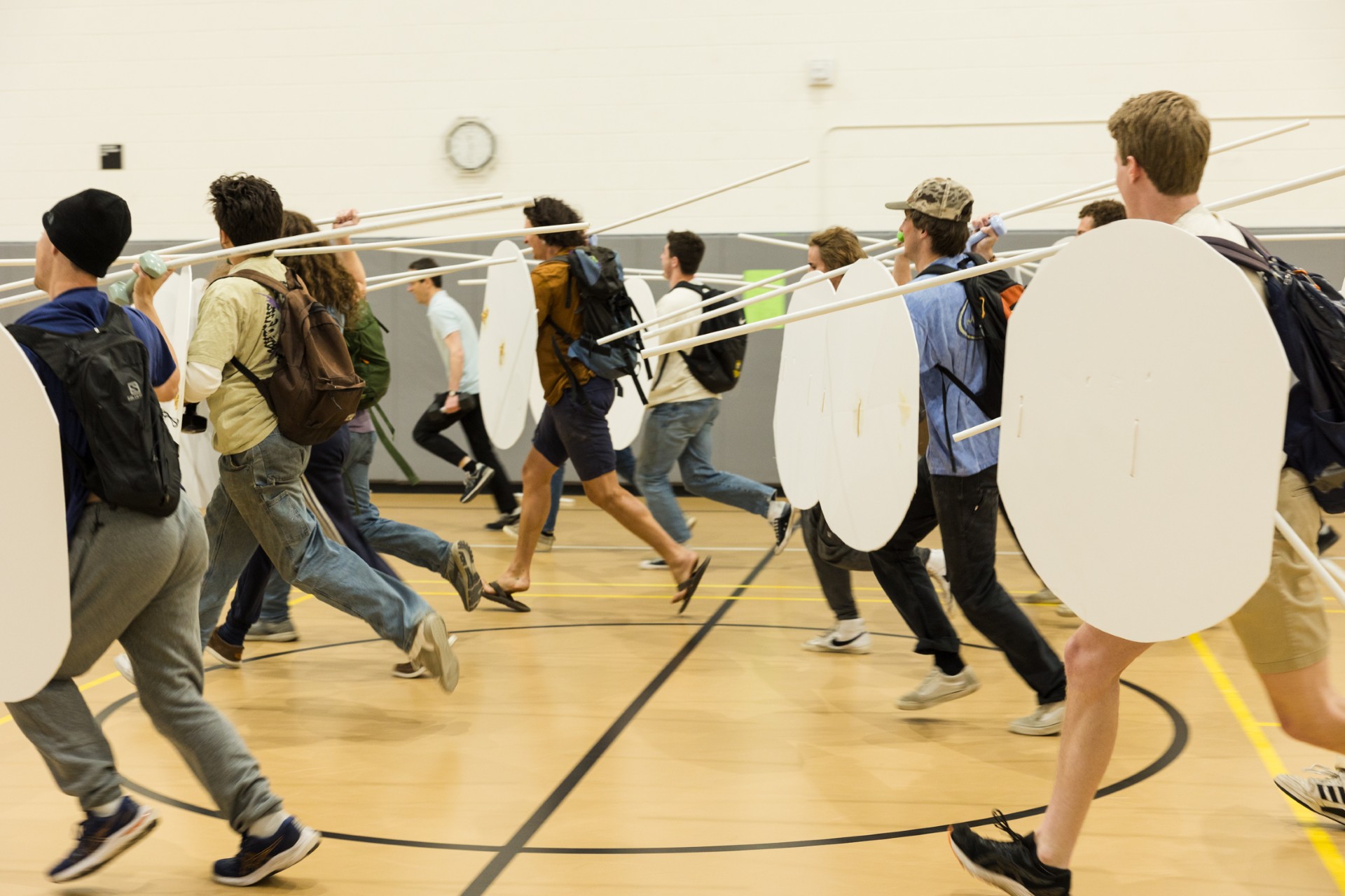 Students in the Spring 2024 Warfare in Greece and Rome course simulate being hoplites by wearing two backpacks, a helmet, and using cardboard silhouettes of a hoplite’s shield and of his weapons, which were cut PVC pipe segments. Associate Professor and Chair of Classics Dr. Richard Fernando Buxton had students fill their backpacks, pockets, and hands with weights that accurately simulated the weight of various pieces of gear, including armor, shield, spear, and sword. Photo by Eileen Broderick.