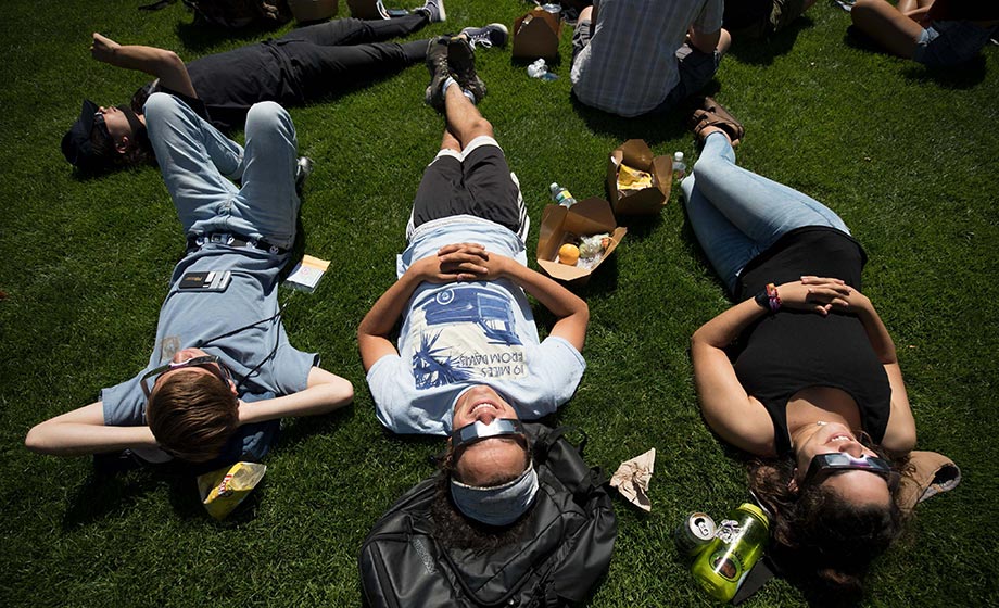 Students laying on grass, looking up